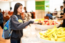 Student reaches for apple at Catlett Marketplace UIOWA
