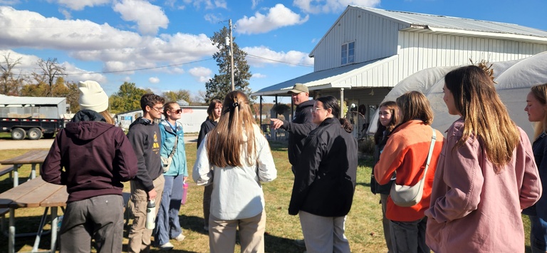 Students gather around to hear Matt Kroul speak about his farm