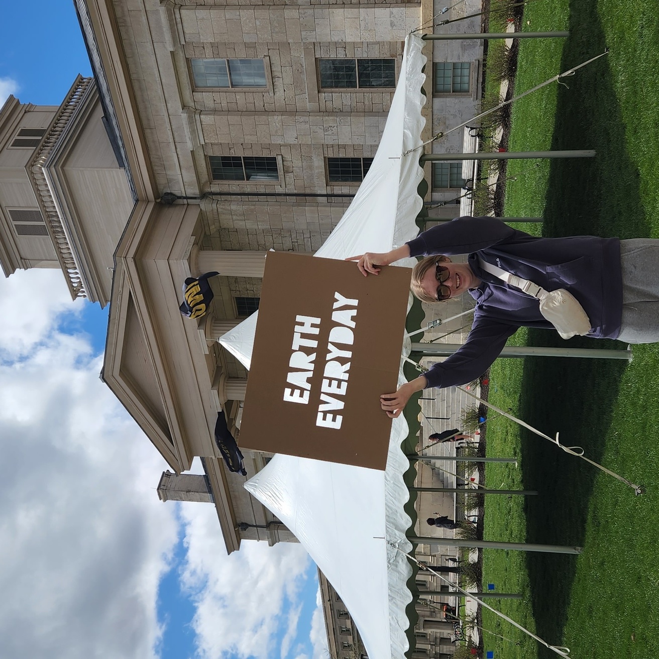 Student holding earth everyday sign on Pentacrest