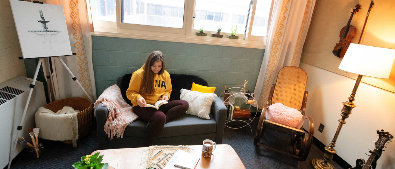 A student sitting on a couch in their dorm room
