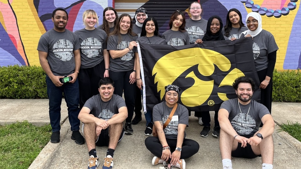 A group of student volunteers on Hawkeye Service Break holding a Tigerhawk flag