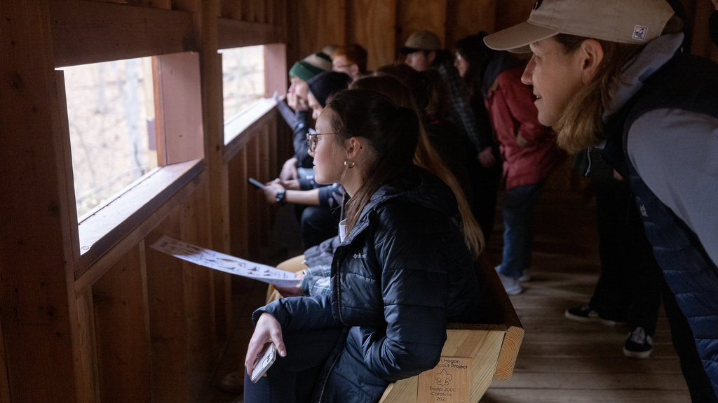 Professor and students observing songbirds from inside a bird blind